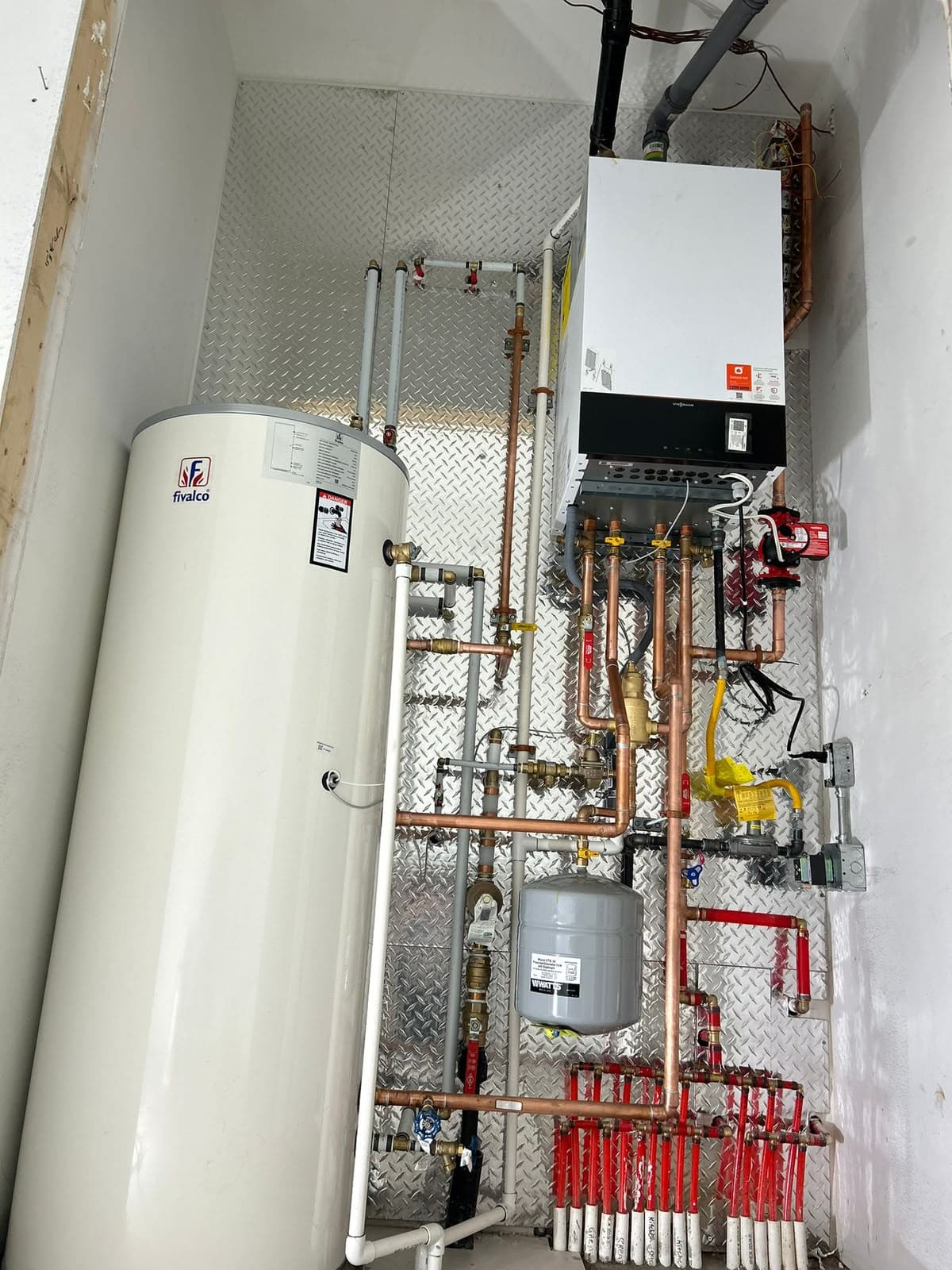 White storage tank beside copper piping and valves in a mechanical room