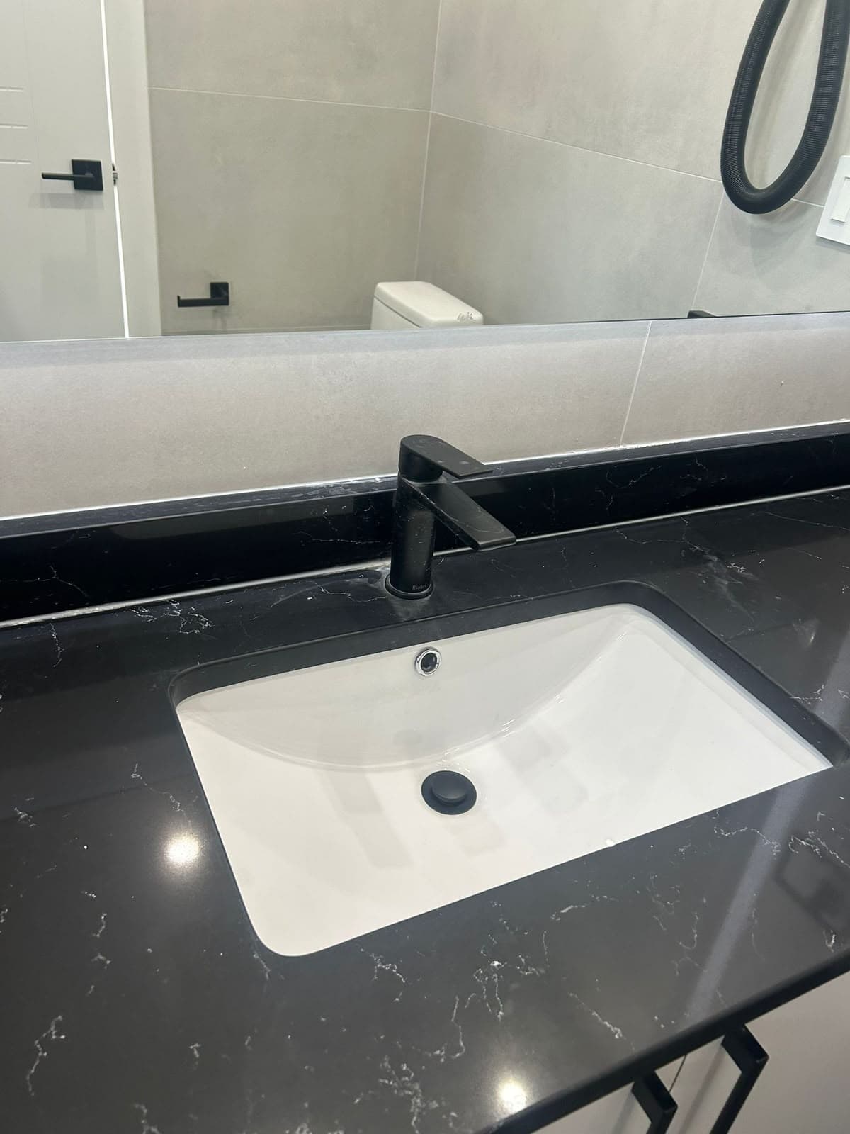 Undermount sink in a black quartz vanity top with a matte black faucet